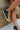 The Elle High-Top Sneaker is a high-top sneaker featuring a nude leather front, a dark grey leather upper, a side star detail, a pink glitter stripe at the heel, an inner side zipper, a lace-up front, and an off-white sole.