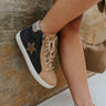 The Elle High-Top Sneaker is a high-top sneaker featuring a nude leather front, a dark grey leather upper, a side star detail, a pink glitter stripe at the heel, an inner side zipper, a lace-up front, and an off-white sole.