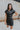 Frontal view of the Can't Live Without Mini Dress that features a black faux-leather material, a collar neck, a short cuffed sleeve, a button-up front, two front pockets at the chest, two front pockets at the bottom, and a mini length.