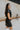 Side view of the Can't Live Without Mini Dress that features a black faux-leather material, a collar neck, a short cuffed sleeve, a button-up front, two front pockets at the chest, two front pockets at the bottom, and a mini length.