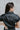 Back view of the Can't Live Without Mini Dress that features a black faux-leather material, a collar neck, a short cuffed sleeve, a button-up front, two front pockets at the chest, two front pockets at the bottom, and a mini length.