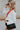 Side view of the Don't Get It Twisted Jacket that features a white faux leather material, a collar neck, a button-up front, a monochromatic white checkered print, front fringe detailing, and a cropped fit.