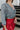 Back view of the Take It Back Top that features a washed black denim material, a V neckline, 3/4 sleeves, a ruched front, a keyhole buttoned back, and an elastic bottom hem at the back.