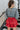 Back view of the Take It Back Top that features a washed black denim material, a V neckline, 3/4 sleeves, a ruched front, a keyhole buttoned back, and an elastic bottom hem at the back.