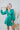 Frontal view of the A Vision Mini Dress that features a green satin material, a monochromatic floral print, a V neckline, a long puffy sleeve, button detailing at the front, a zipper back closure, and a flowy fit.