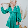 Frontal view of the A Vision Mini Dress that features a green satin material, a monochromatic floral print, a V neckline, a long puffy sleeve, button detailing at the front, a zipper back closure, and a flowy fit.