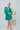 Frontal view of the A Vision Mini Dress that features a green satin material, a monochromatic floral print, a V neckline, a long puffy sleeve, button detailing at the front, a zipper back closure, and a flowy fit.
