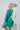 Side view of the A Vision Mini Dress that features a green satin material, a monochromatic floral print, a V neckline, a long puffy sleeve, button detailing at the front, a zipper back closure, and a flowy fit.