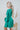 Side view of the A Vision Mini Dress that features a green satin material, a monochromatic floral print, a V neckline, a long puffy sleeve, button detailing at the front, a zipper back closure, and a flowy fit.