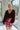 Frontal view of the Take Me Out Bodysuit that features a burgundy velvet material, a surplice neckline with a clasp closure, a long sleeve with a smocked wrist, and a bikini bottom with a snap closure.