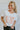 Front view of model wearing the Howdy Cropped Graphic Tee, that features a white cotton material, a round neck, a short sleeve, pink, orange, and purple text that reads "Howdy", and a raw hem