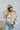 Frontal view of the Switch It Up Sweater that features a tan knit material, an ivory geometric print, a round neck, long cuffed sleeves, and a loose fit.