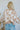 Back view of the Switch It Up Sweater that features a tan knit material, an ivory geometric print, a round neck, long cuffed sleeves, and a loose fit.