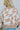 Back view of the Switch It Up Sweater that features a tan knit material, an ivory geometric print, a round neck, long cuffed sleeves, and a loose fit.