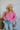 Frontal view of the Keep On Dreamin' Sweater that features a fuchsia knit material, a knit pattern, a V neckline, a long cuffed sleeve, and a V back with an adjustable tie closure.