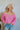 Frontal view of the Keep On Dreamin' Sweater that features a fuchsia knit material, a knit pattern, a V neckline, a long cuffed sleeve, and a V back with an adjustable tie closure.