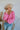 Frontal view of the Keep On Dreamin' Sweater that features a fuchsia knit material, a knit pattern, a V neckline, a long cuffed sleeve, and a V back with an adjustable tie closure.