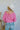Back view of the Keep On Dreamin' Sweater that features a fuchsia knit material, a knit pattern, a V neckline, a long cuffed sleeve, and a V back with an adjustable tie closure.