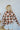 Back view of the Let's Go West Jacket that features an ivory colored material, a rust and brown plaid pattern, a collar neck, a button-up front, two front pockets, and long cuffed sleeves.