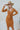 Front view of model wearing the Slipped Away Mini Dress in Camel, that has a camel colored knit material, a surplice neckline, long sleeves, ruched side detailing with adjustable strings, a side slit, a midi length, and a tight fit
