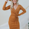 Front view of model wearing the Slipped Away Mini Dress in Camel, that has a camel colored knit material, a surplice neckline, long sleeves, ruched side detailing with adjustable strings, a side slit, a midi length, and a tight fit