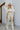 Frontal view of the Keep Shining Pants that features a gold shimmer pleather material, a high-rise waist, a button and zipper front closure, a front pleat down the legs, and a flare leg fit.