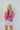 Frontal view of the Stay Cozy Top that features a pink colored thermal material, a round neck, long cuffed sleeves, exposed hems through out, a lettuce edge bottom hem, and a flowy fit.