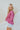 Side view of the Stay Cozy Top that features a pink colored thermal material, a round neck, long cuffed sleeves, exposed hems through out, a lettuce edge bottom hem, and a flowy fit.