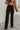Frontal view of the Let's Chat Pants that features a black colored material, a high-rise waist, a sweetheart cut waist hemline, a seam down the front legs, a wide leg fit, and a back zipper closure.