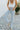 Frontal view of the Signature 8: Crossed Paths Jeans that features a medium wash denim, a front button and zipper closure, crossover waist line, two front pockets, distressing through out, a raw bottom hem, two back pockets, and a wide leg fit.