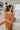Frontal view of the Neon Moon Mini Dress that features a rust colored knit material, a swirl checkered pattern, a straight neckline, a sleeveless design with thick straps, a tight fit, and a mini length.