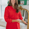 Frontal view of the Frontrunner Dress that features a red colored material, a collar neck, a button-up front, long cuffed sleeves, a front pocket, a curbed bottom hem, and a mini length.