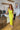 Full body view of model wearing the Shine Bright Dress which features neon lime satin fabric with a lining, a side slit, a scooped neckline, tie spaghetti straps, and a side zipper and hook closure.