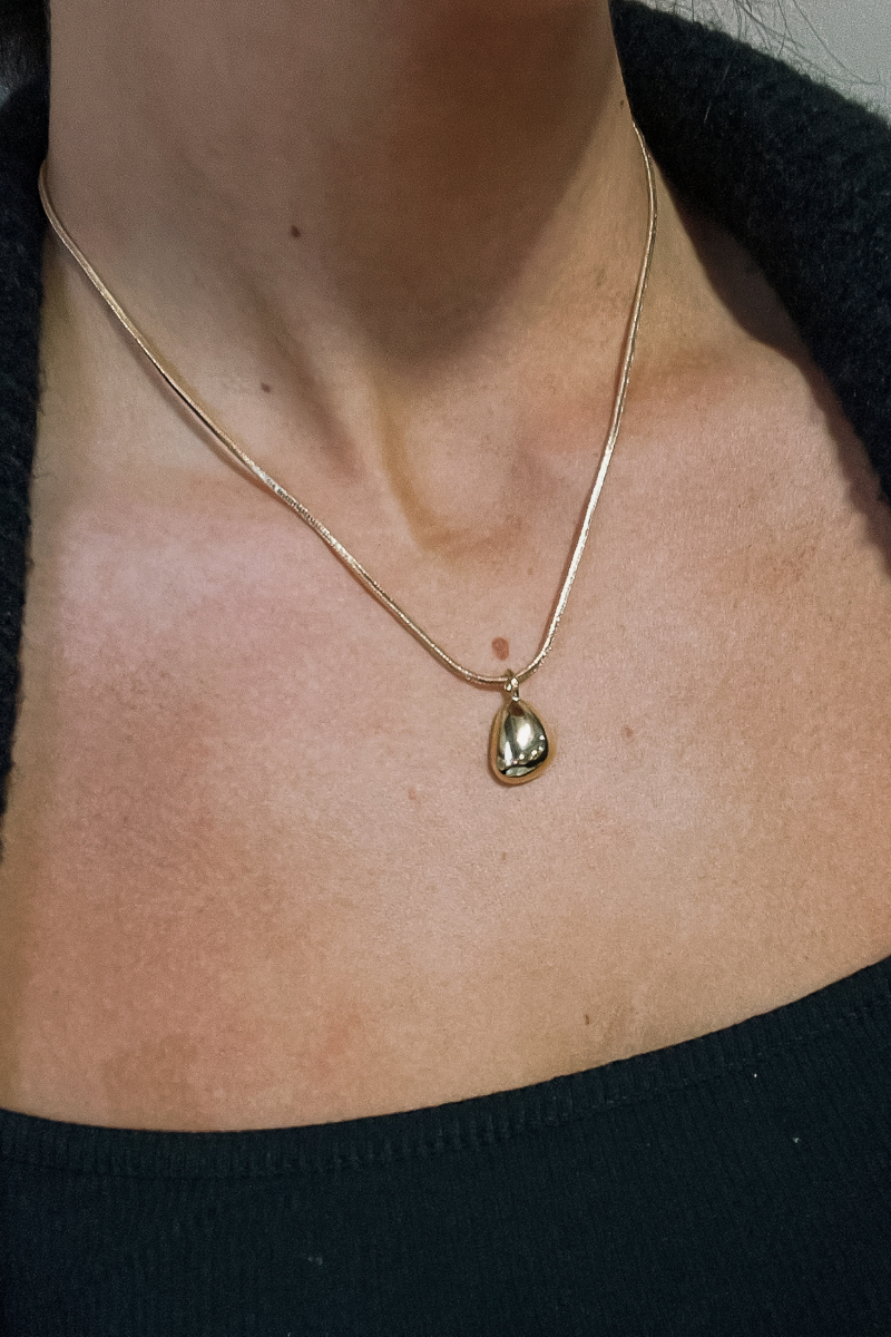 Close up view of model wearing the Maeve Gold Slinky Medallion Necklace which features one gold layer with teadrop shaped medallion and adjustable clasp closure.