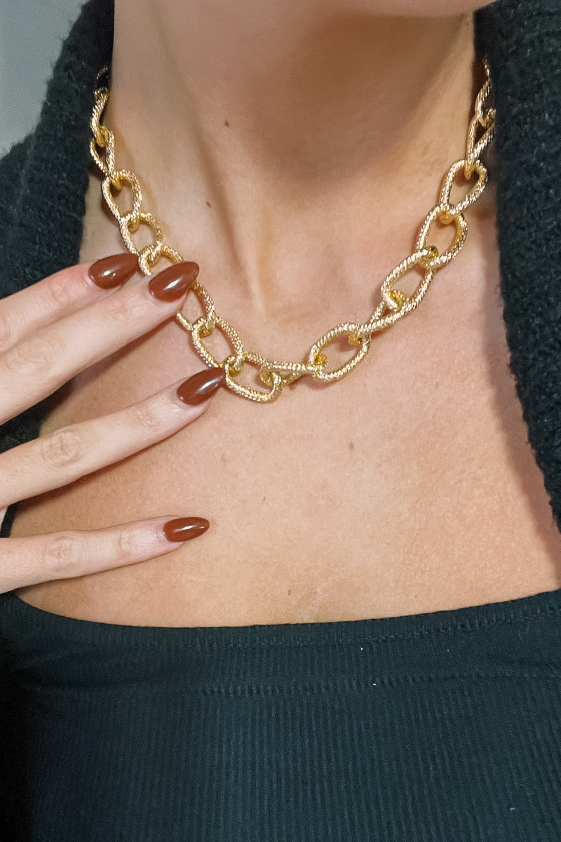Close up view of model wearing the Ayla Gold Textured Chain Link Necklace which features hammered gold chain links with an adjustable clasp closure.