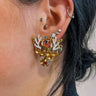 Close up of model wearing the Reindeer Gold Multi Stone Earrings that feature gold reindeer shaped studs with white antlers and multi color stones.