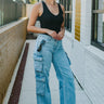 Front view of model wearing the Dakota Cargo Jeans that have blue denim fabric, pockets, a front zipper with a button closure, belt loops and wide legs