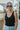 Front view of model wearing the Best Of The Best Tank Top that has double-layered black knit fabric, a v-neckline and back, and a sleeveless design