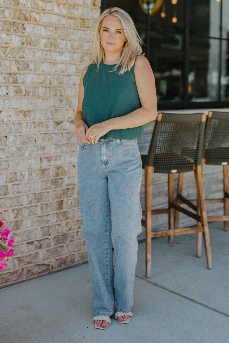 Front view of model wearing the Brentwood Wide Leg Jeans that have medium wash denim fabric, brown stitching, a front zipper with a button closure, two front pockets, two back pockets, belt loops and wide legs.