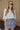 Front view of model wearing the Bring It On Skirt that has grey lightweight fabric, two front pockets with drawstring ties, mini length and an elastic waistband with drawstring ties