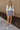 Full body front view of model wearing the Bring It On Skirt that has grey lightweight fabric, two front pockets with drawstring ties, mini length and an elastic waistband with drawstring ties