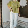 Full front view of model wearing the How Romantic Top that has olive green fabric, a peplum body style, a round neckline, short balloon sleeves, and a back keyhole with a button closure