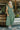 Front view of model wearing the Love Story Midi Dress that has green fabric, midi length, side pockets, a smocked upper body, a scoop neckline, and ruffle straps.