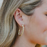 Side view of model wearing the Full of Spirit Hoops which features medium, open hoops with gold rope design.