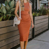 Front view of The Movement Dress In Rust features rust knit fabric, midi length, ruched side details, a side slit, a round neckline and a sleeveless design.