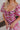 Close up view of model wearing the Falling For You Floral Dress which features berry pink, purple, green and white sheer fabric, floral print, berry pink lining, front slit, ruffle layered hem, sweetheart neckline, short puff sleeve with ruffle hem and mo