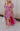Full body view of model wearing the Falling For You Floral Dress which features berry pink, purple, green and white sheer fabric, floral print, berry pink lining, front slit, ruffle layered hem, sweetheart neckline, short puff sleeve with ruffle hem and m