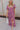 Full body view of model wearing the Falling For You Floral Dress which features berry pink, purple, green and white sheer fabric, floral print, berry pink lining, front slit, ruffle layered hem, sweetheart neckline, short puff sleeve with ruffle hem and m