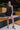 Full body view of model wearing the All Over Again Romper which features black lightweight fabric, shorts lining, tiered ruffle design, round neckline, sleeveless and monochromatic back zipper with hook closure.
