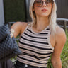 Front view of model wearing the Keep It Simple Striped Tank that has ribbed fabric with a black and tan stripe pattern, a cropped waist, a round neckline and a sleeveless design
